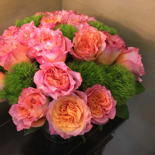 Pink and peach roses arranged with green moss in a low container