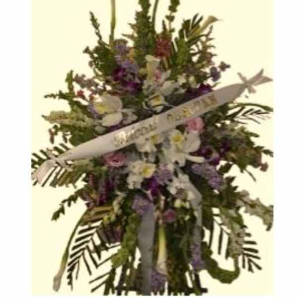 Standing floral spray with white ribbon and mixed purple, pink, and white flowers