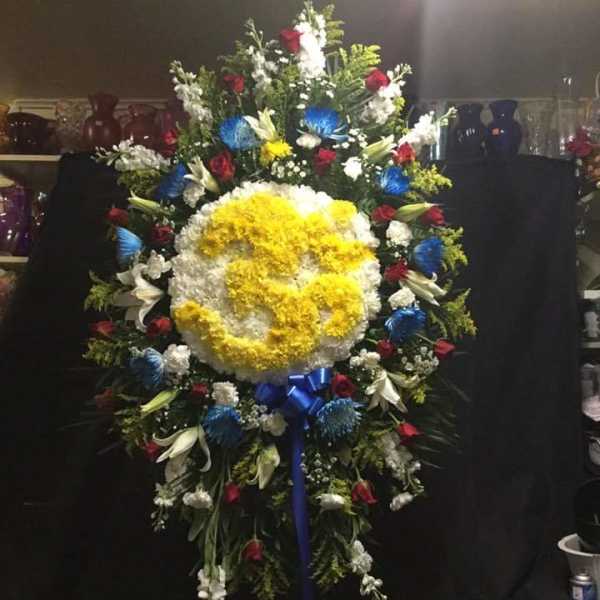 Large standing floral wreath with a yellow and white center and red, blue, and white flowers