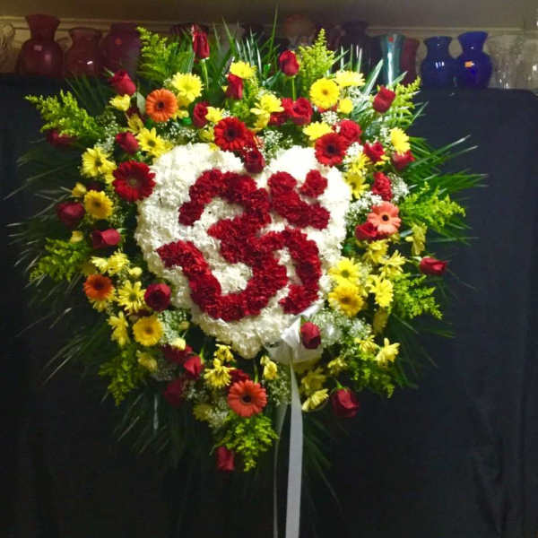 Heart-shaped floral wreath with red and white flowers and a ribbon