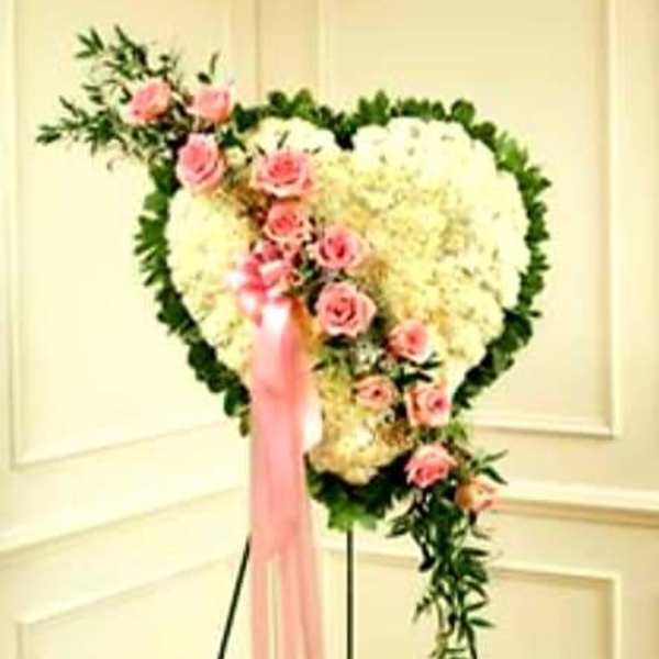 Heart-shaped floral spray with pink roses and white flowers on a stand