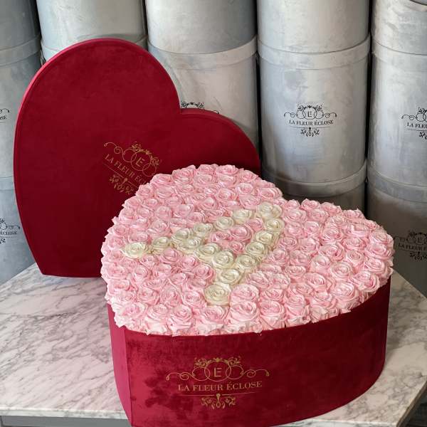 Heart-shaped box filled with pink roses and a cream ribbon design
