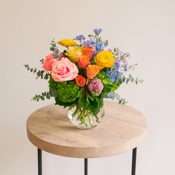 Colorful mixed bouquet in a clear glass vase on a round table