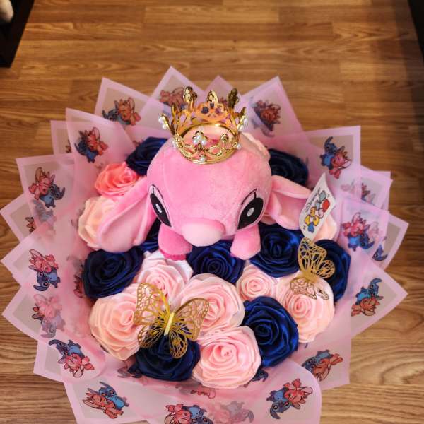 Pink plush toy surrounded by blue and pink roses with a gold crown