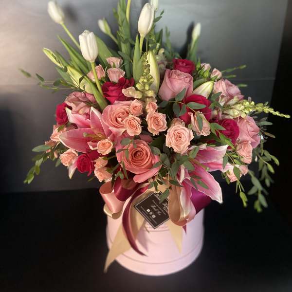Pink and white floral arrangement in a round hat box