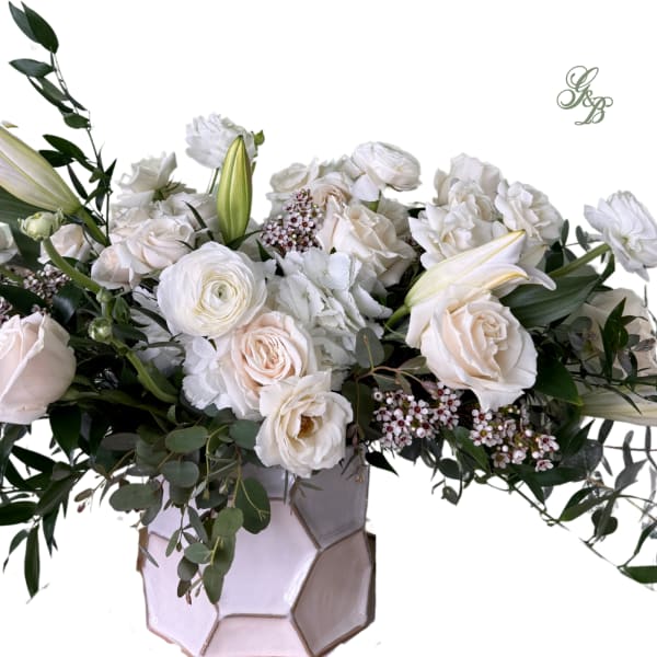 White floral arrangement in a geometric vase with roses and lilies