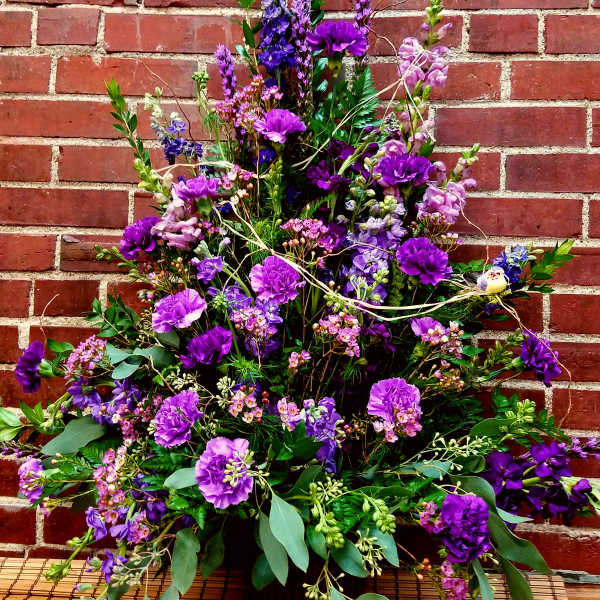 Tall purple floral arrangement in a dark vase