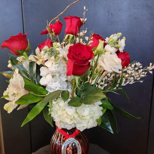 Red roses and white flowers arranged in a glass vase