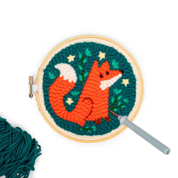 Embroidery hoop with a fox design and a needle tool