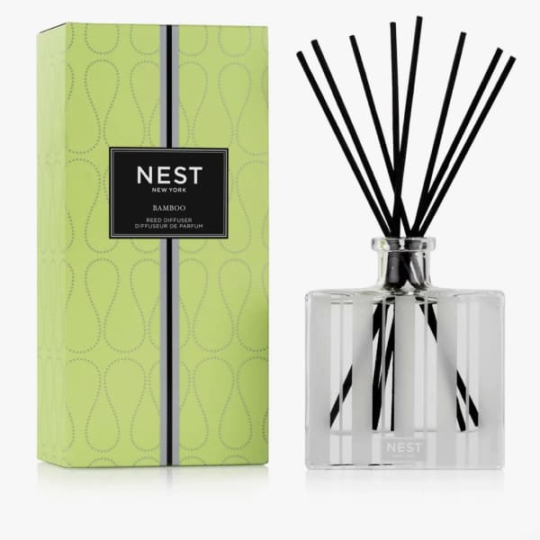 Reed diffuser in a clear glass bottle with black reeds and a green box