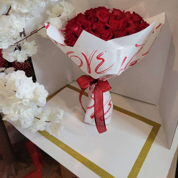 Bouquet of red roses wrapped in white paper with a red ribbon