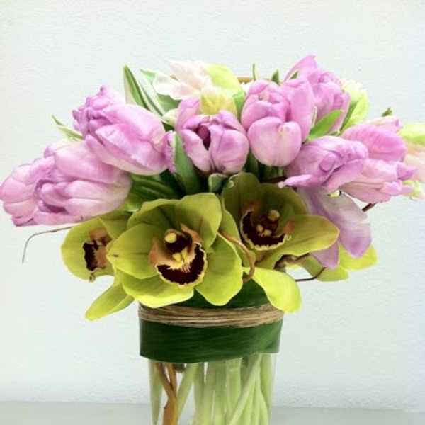 Pink tulips and green orchids arranged in a glass vase