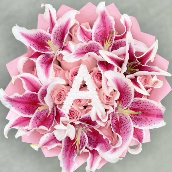 Pink lilies and roses arranged in a bouquet with pink wrapping