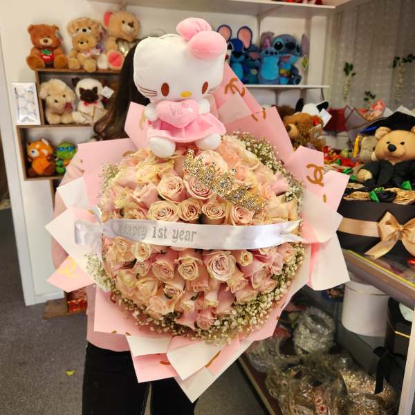 Pink rose bouquet topped with a Hello Kitty plush and ribbon