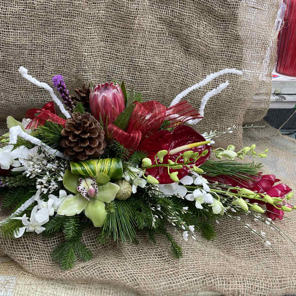 Long floral arrangement with red, white, and green blooms on burlap