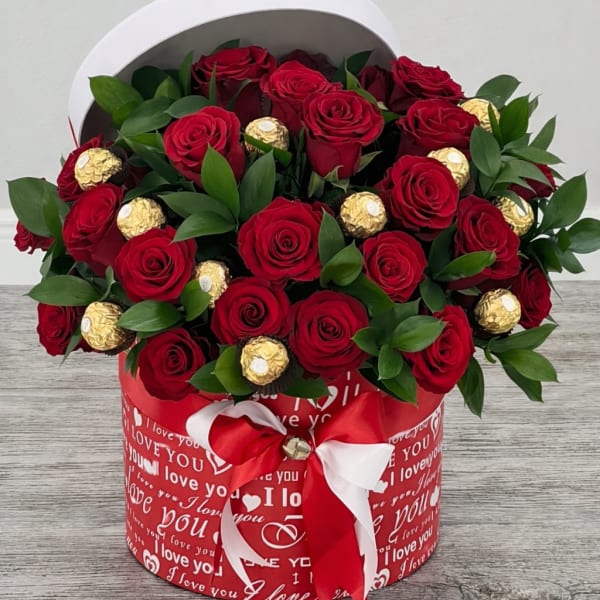 Red roses and gold-wrapped chocolates in a heart-themed gift box