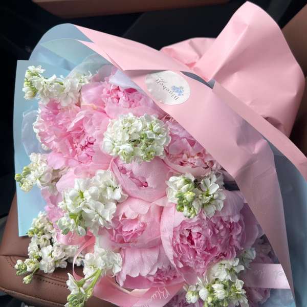 Pink bouquet with white flowers wrapped in pastel paper