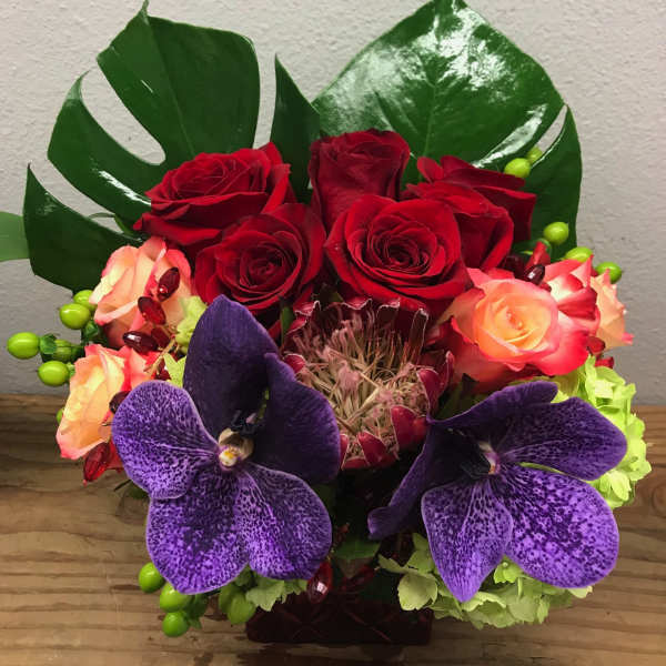 Bouquet of red and peach roses with purple orchids in a vase