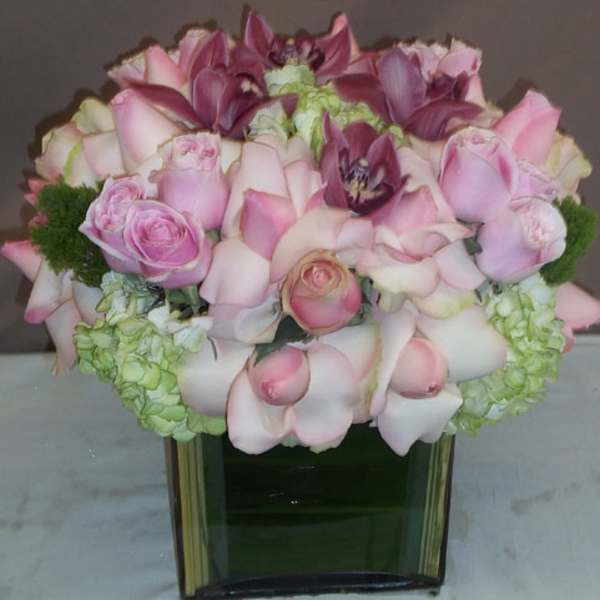 Pink roses and calla lilies arranged in a square glass vase