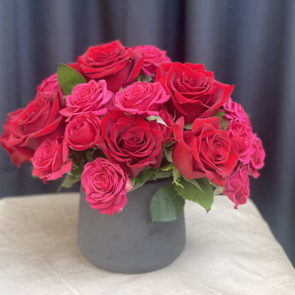 Pink and red roses arranged in a gray vase