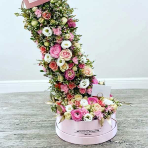 Tall pink floral arrangement in a round box with a matching top box
