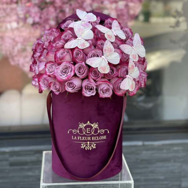 Pink roses in a velvet hatbox with white butterfly decorations
