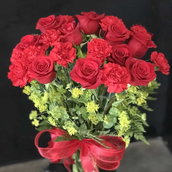 Red roses and carnations in a bouquet with a red ribbon