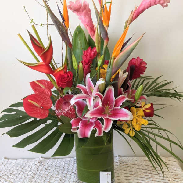 Tropical bouquet with pink lilies and red anthuriums in a glass vase