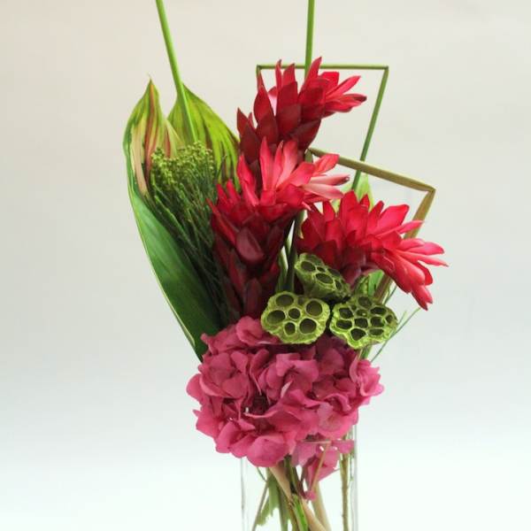 Tropical bouquet with red and pink flowers in a clear glass vase