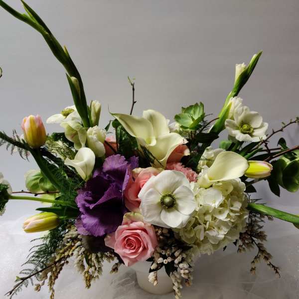 Mixed bouquet with white calla lilies, pink roses, and purple blooms in a vase