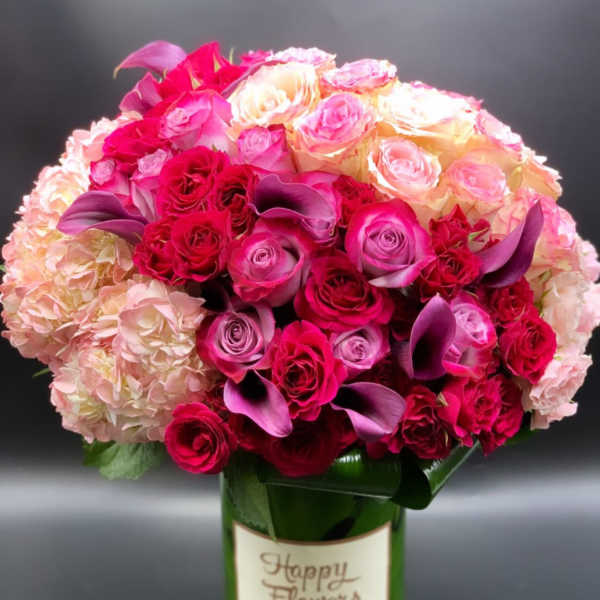 Pink and cream roses with purple calla lilies in a green vase