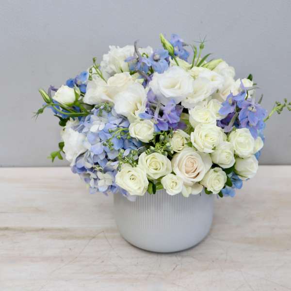 White and blue floral arrangement in a white vase