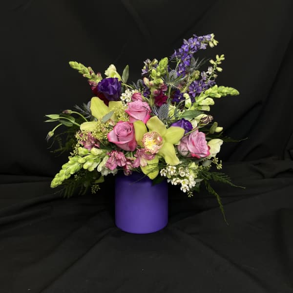 Mixed bouquet in a purple vase with pink, yellow, and purple flowers