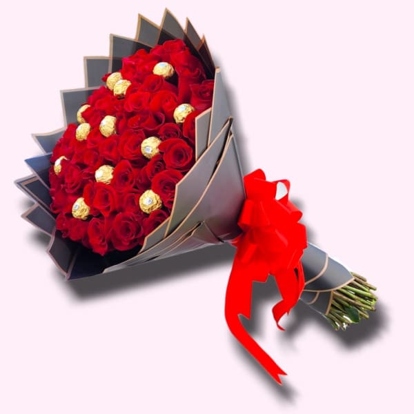 Bouquet of red roses with gold-wrapped chocolates in dark paper wrap and red bow