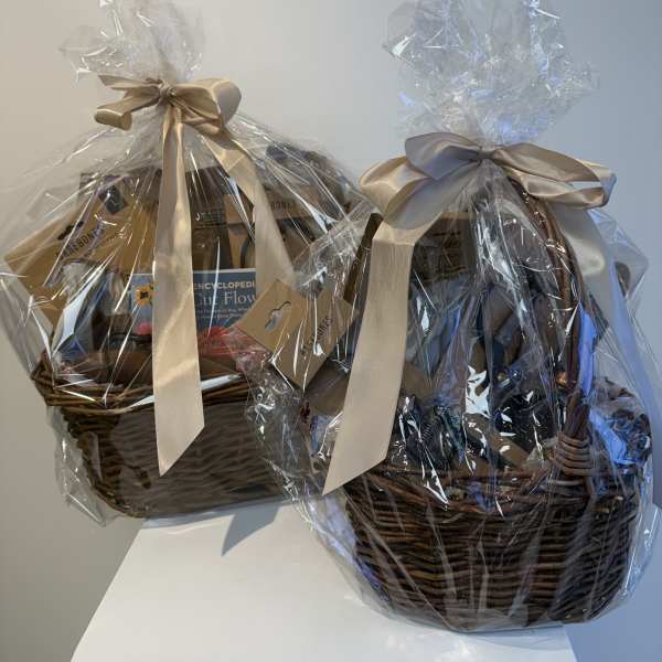 Two wrapped gift baskets with satin bows and books inside