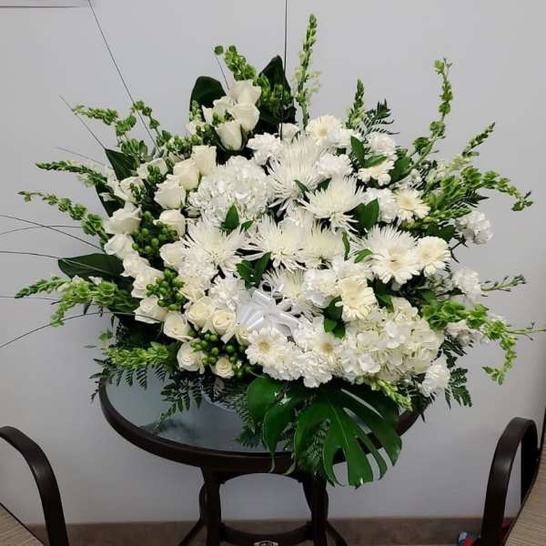 Large white floral arrangement with roses, daisies, and orchids