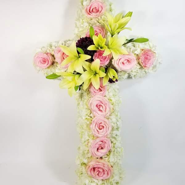 Floral cross with pink roses and pale lilies on a white background