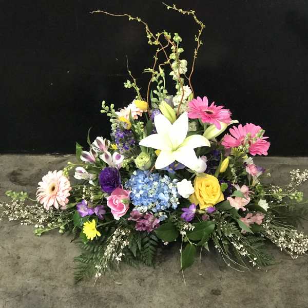 Colorful floral arrangement with a white lily, gerbera daisies, and roses
