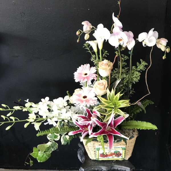 Mixed floral arrangement in a wicker basket with pink and white blooms