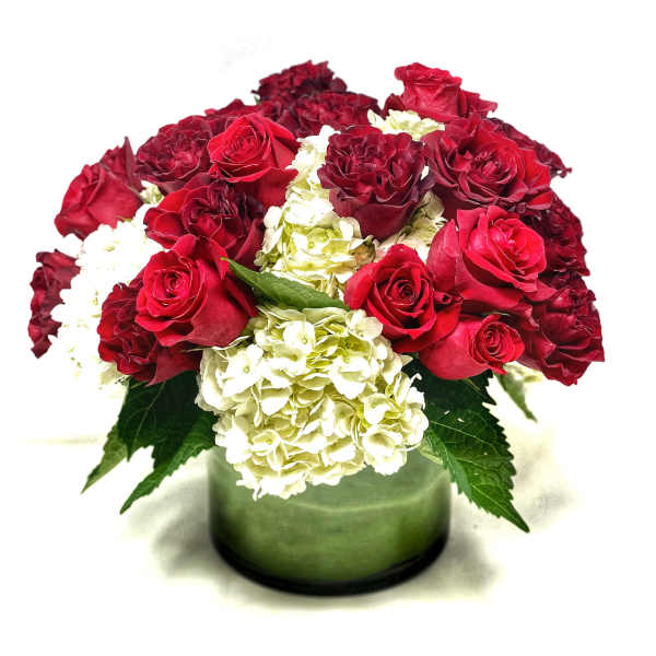 Red roses and white hydrangeas in a green glass vase