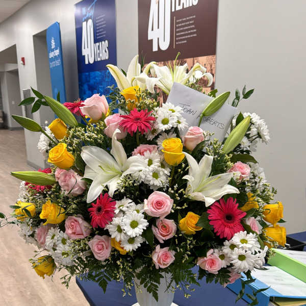 Large mixed flower arrangement in a white pedestal vase