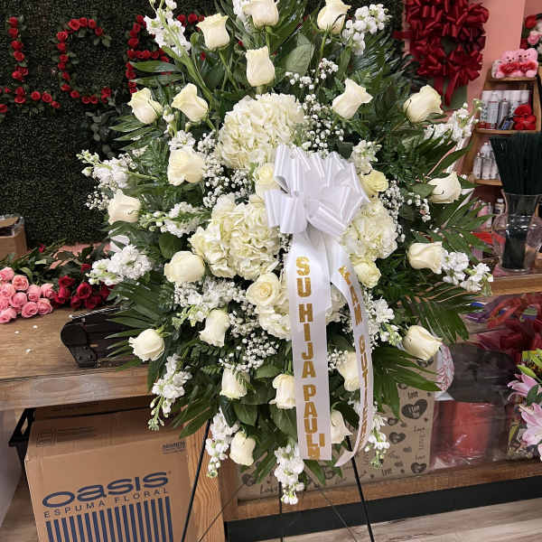 Large standing spray of white roses and hydrangeas with ribbons on a black easel