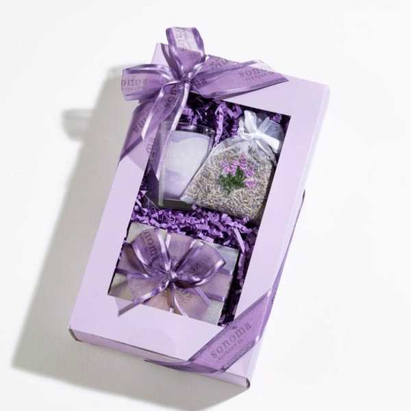 Lavender-themed gift box with candle, sachet, and small wrapped items tied with purple ribbon