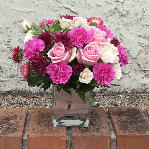 Pink and white roses with carnations in a clear glass vase