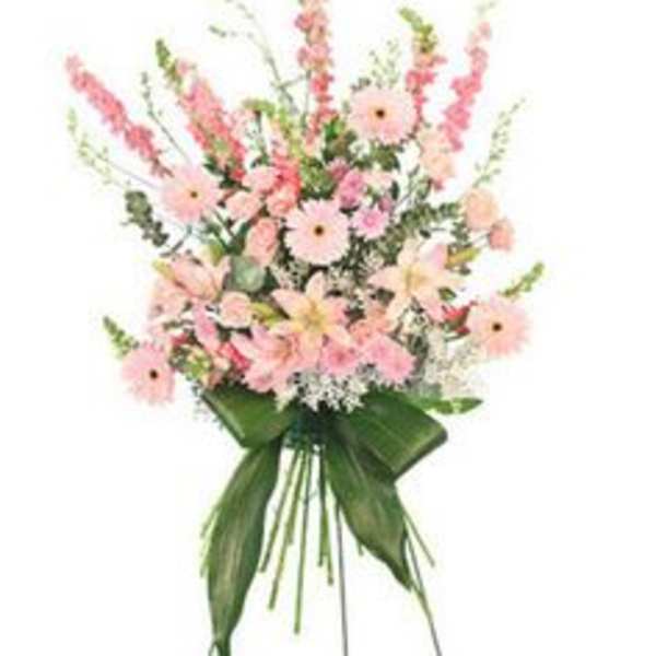 Tall standing spray of pink flowers with large green leaves on a metal easel