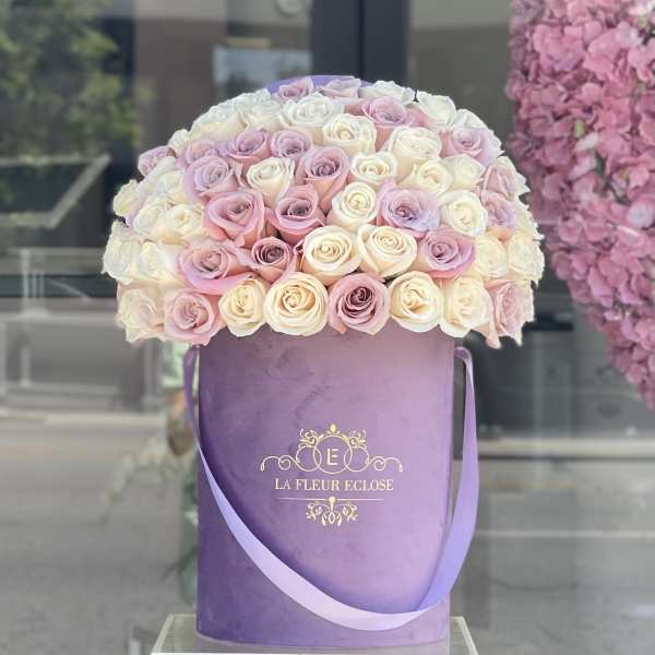 Round bouquet of pastel roses in a purple hatbox