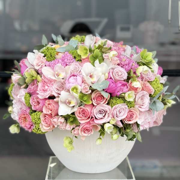 Pink and white roses with orchids in a white vase