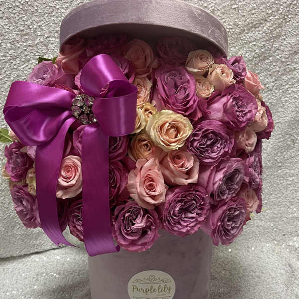 Pink and purple roses in a lavender hatbox with a satin ribbon