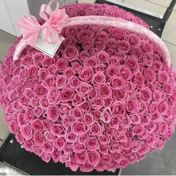 Large dome of tightly packed pink roses with a pink ribbon and gift tag on top