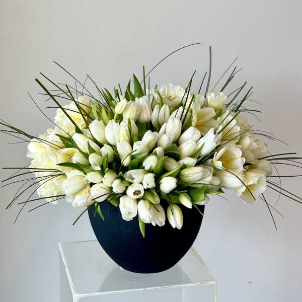 White tulips arranged in a dark round vase